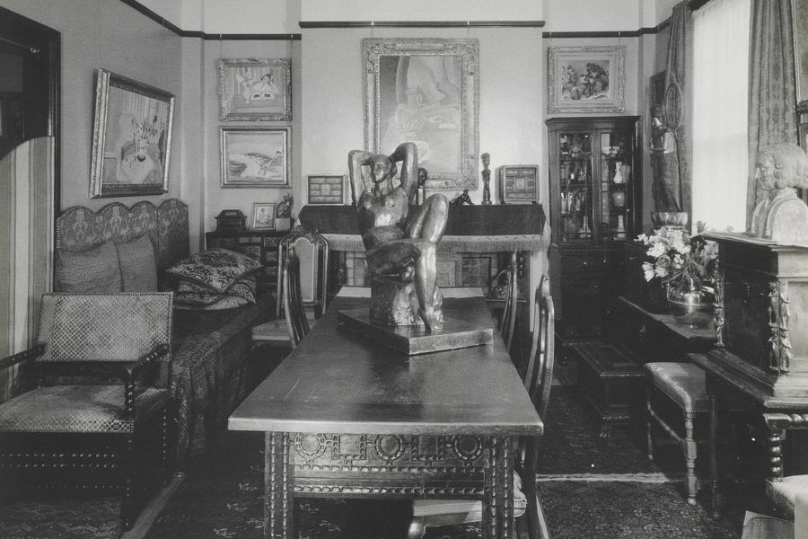 A view of the front room of Claribel Cone's apartment in Baltimore, MD. 1941. Pictured is the art collection hanging on each wall along with other textiles and furniture crowded into the room.